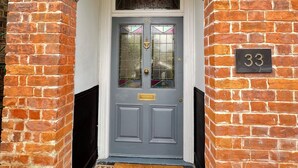 A grey double door with a number '33' above it, flanked by brick walls and an archway. - Transvaal House Ely  (Ely)