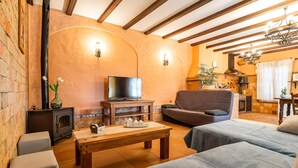 Ein gemütliches Wohnzimmer mit Kamin, Fernseher, einer Couch und einem Essbereich.