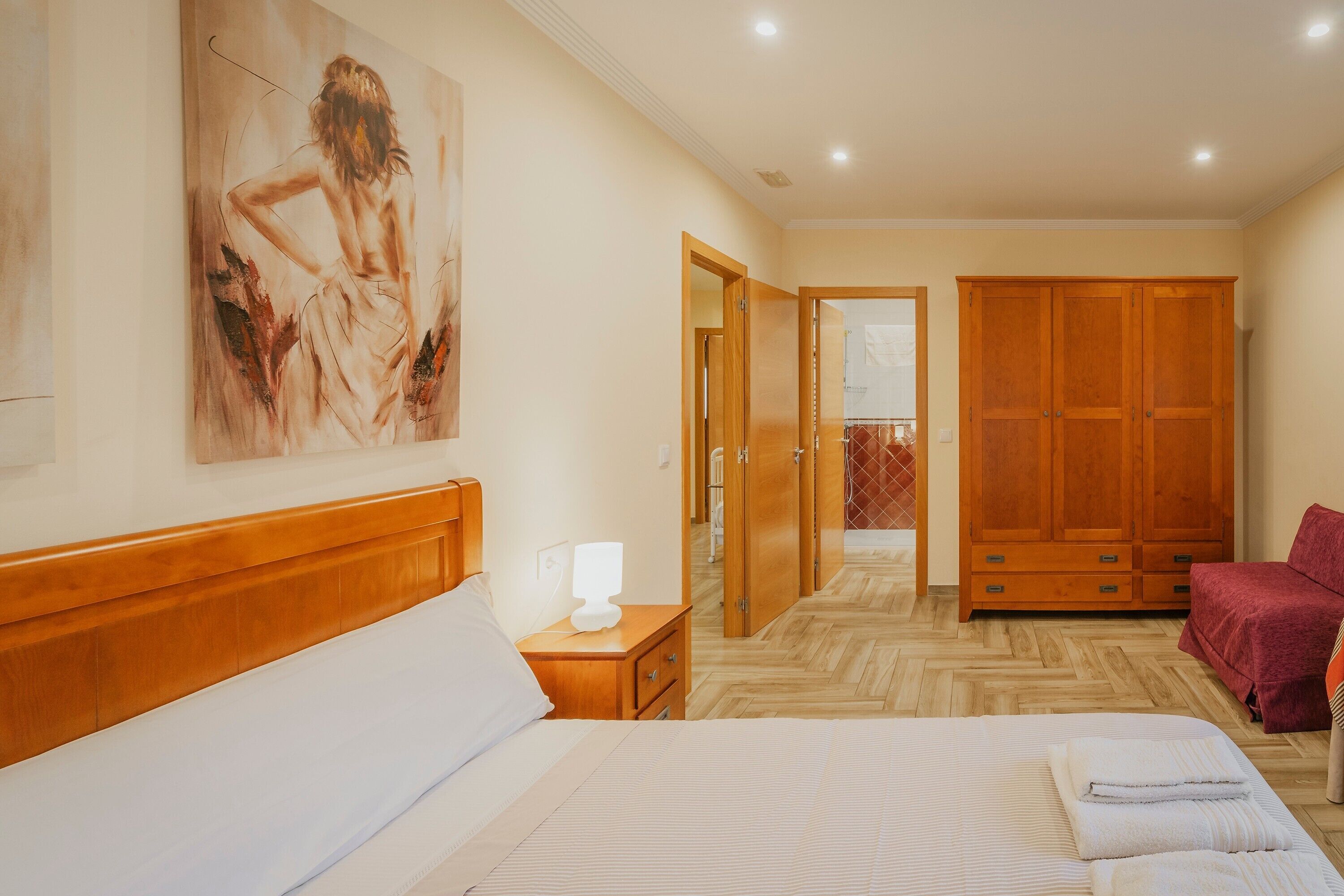 Une chambre d’hôtel avec un lit, une table de chevet, une armoire en bois et un tableau au mur.