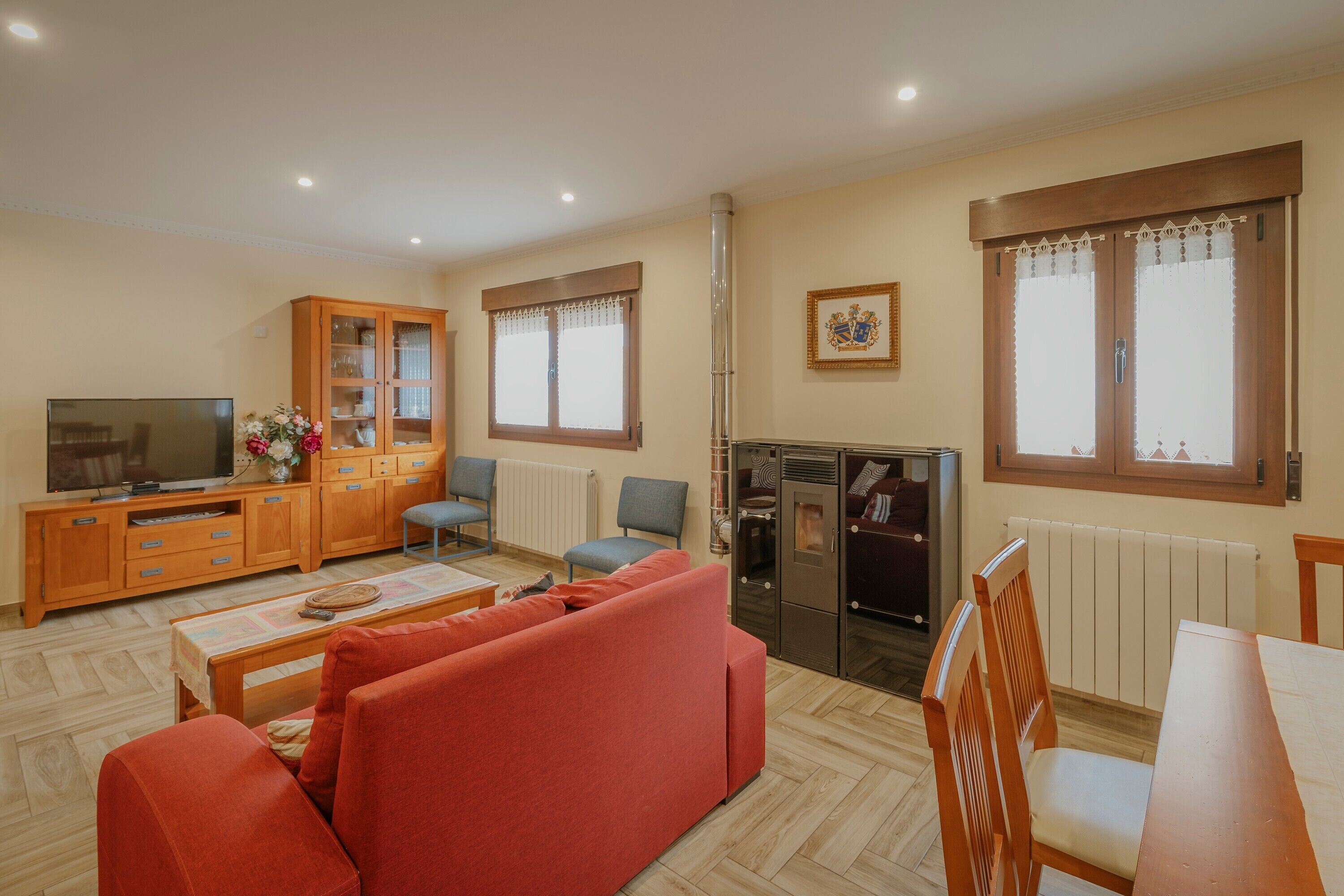 Una sala de estar con sofá, sillones, televisor, mueble y radiador.