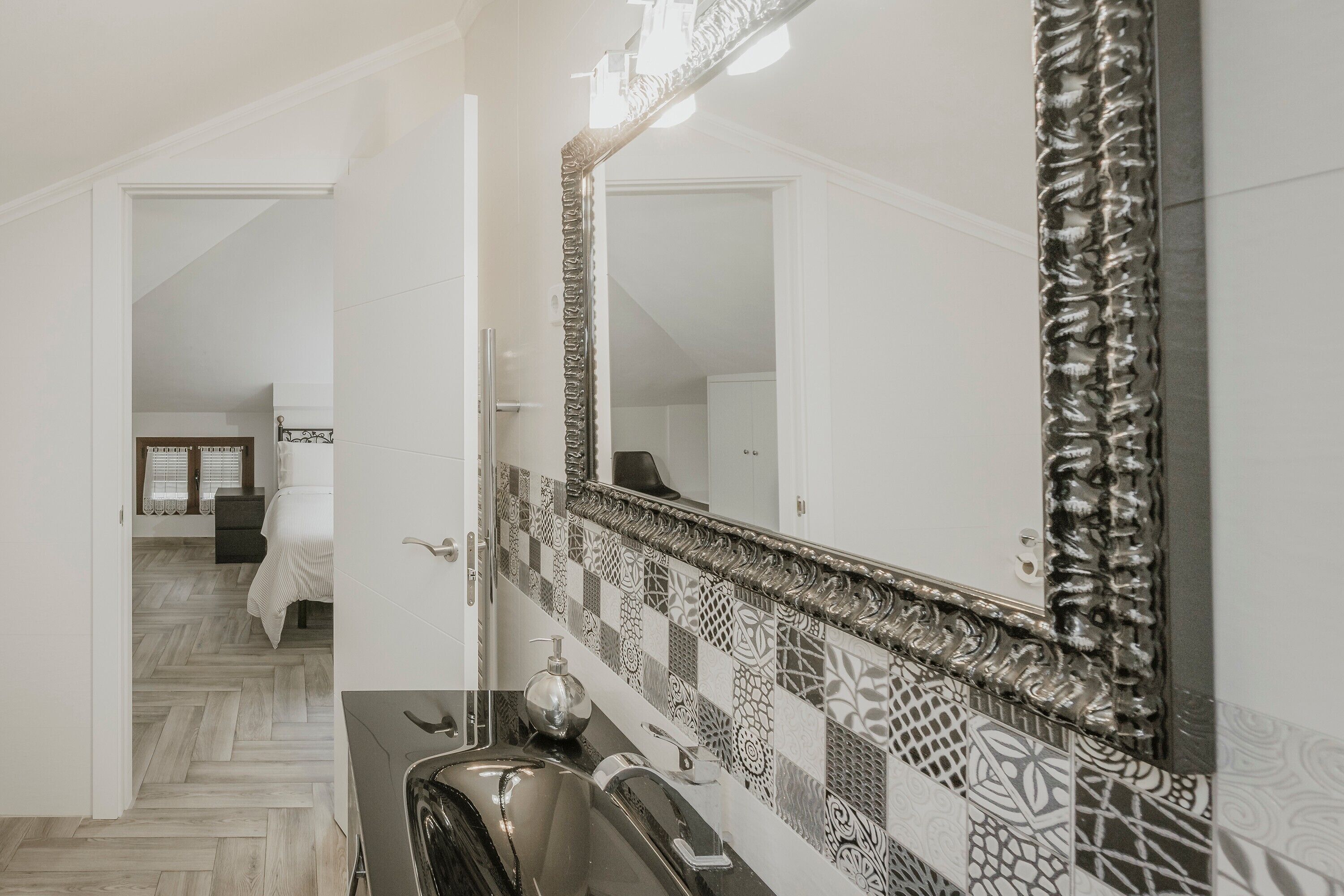 Un baño con salpicadero de azulejos, un lavabo y un espejo.