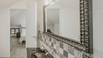 Un baño con salpicadero de azulejos, un lavabo y un espejo.