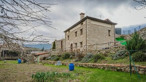A stone building with a garden in front, a clear sky, and a distant mountain. - Torres 1 in Valdivielso Valley, Mountain Views & Garden (MERINDAD DE VALDIVIELSO)