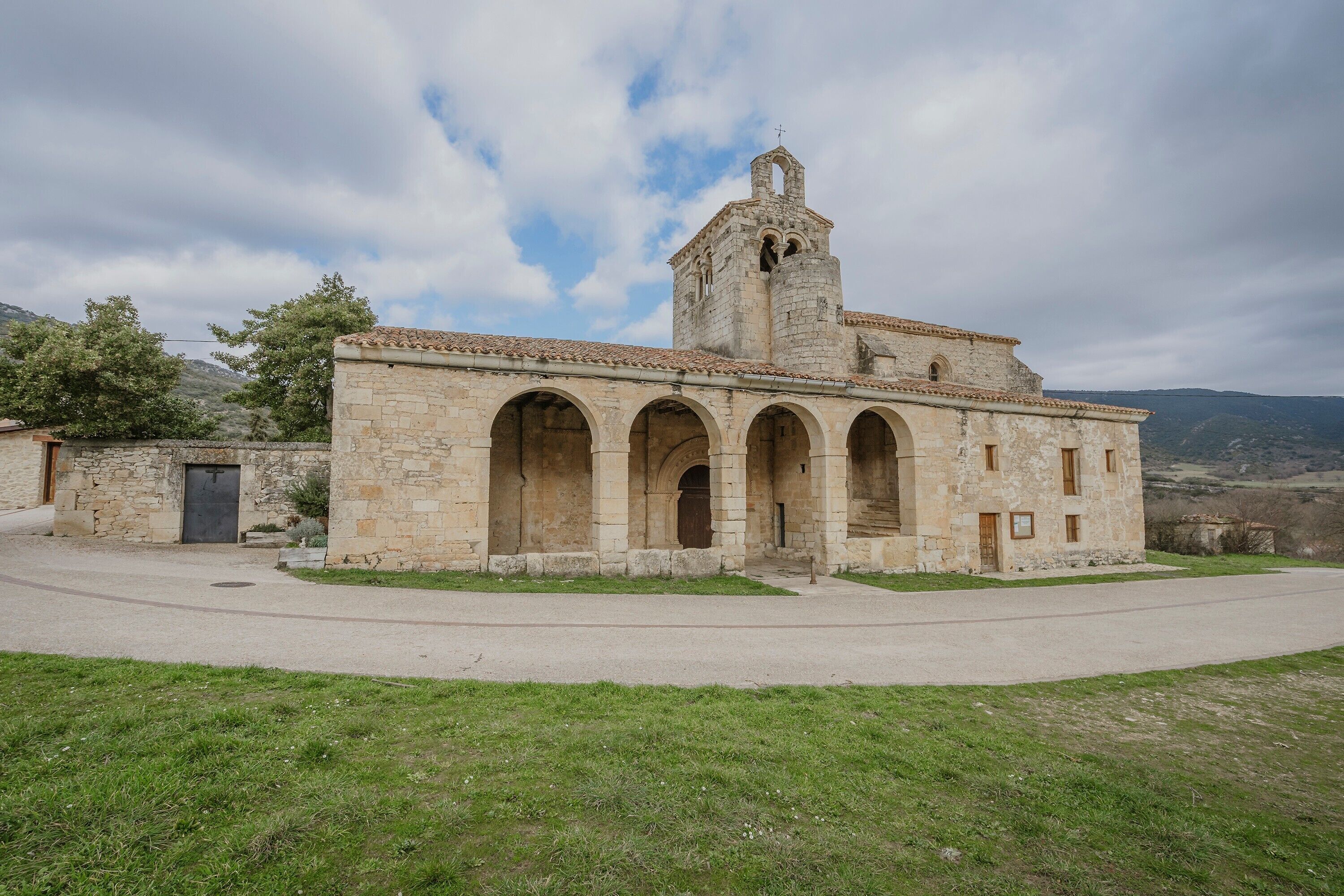 Un edificio de piedra con una torre de campanas, ventanas de arco y una puerta.