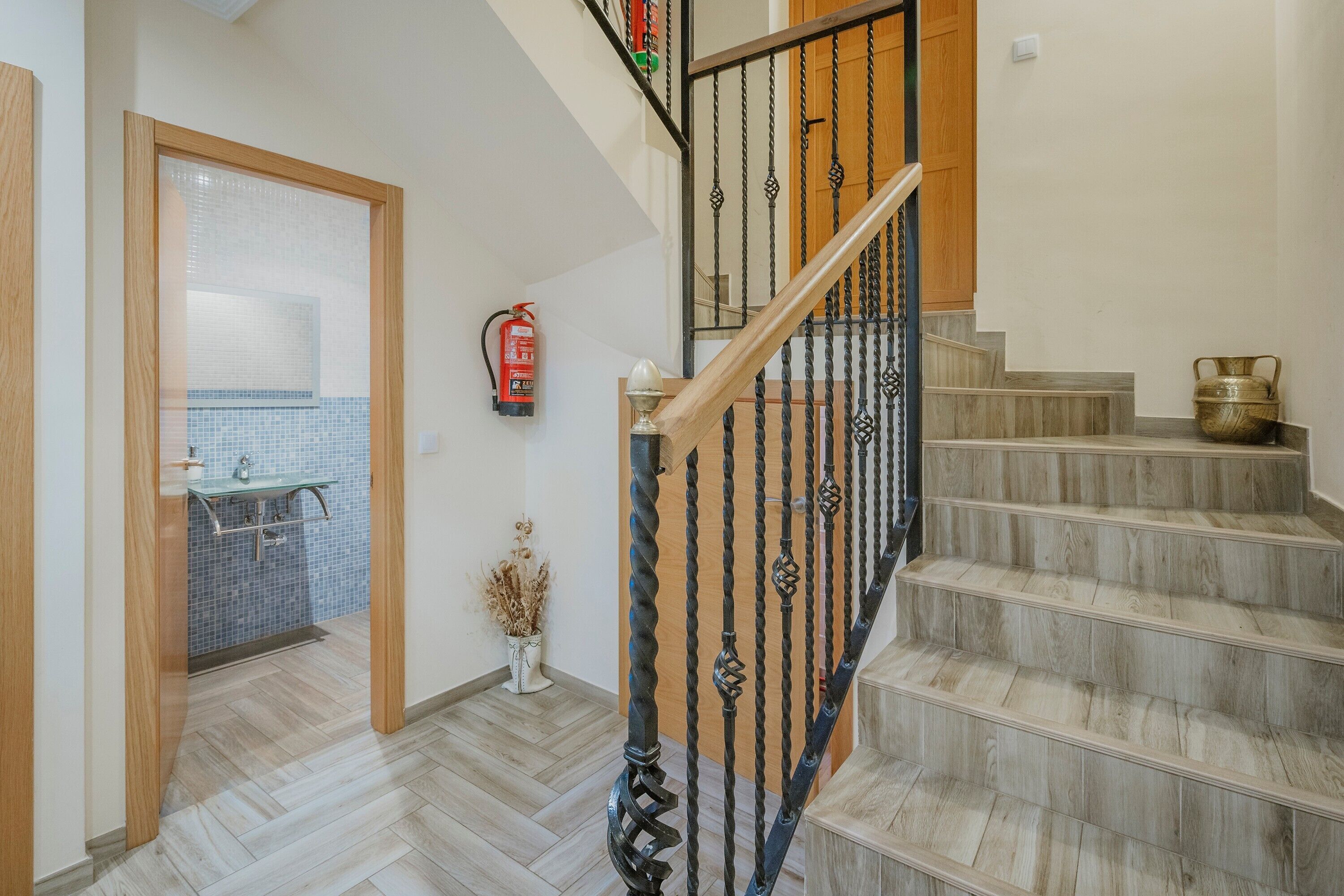 Un escalier avec une rampe en bois et des balustres noires, menant au deuxième étage.