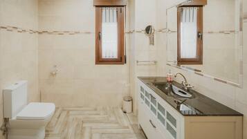 Un baño con inodoro, lavamanos, espejo y paredes con azulejos.