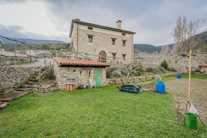 A stone building with a green door, a small attached structure, and a grassy yard.