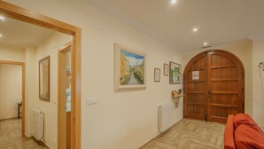 A hallway with wooden flooring, a red sofa, and a wooden door with a sign. - Torres 1 in Valdivielso Valley, Mountain Views & Garden (MERINDAD DE VALDIVIELSO)