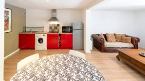 A compact living space with a kitchenette, a washing machine, a microwave, a refrigerator, a sofa, and a coffee table. - Apartment 'Appartement Dans Maison Urcuit' with Mountain View, Private Pool and Wi-Fi (Urcuit)