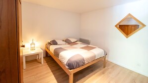 A bedroom with a wooden bed, a bedside table with a lamp, and a mirror on the wall. - Apartment 'Appartement Dans Maison Urcuit' with Mountain View, Private Pool and Wi-Fi (Urcuit)