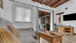 Een moderne woonkamer met een bank, een houten tafel en een aan de muur bevestigde televisie.