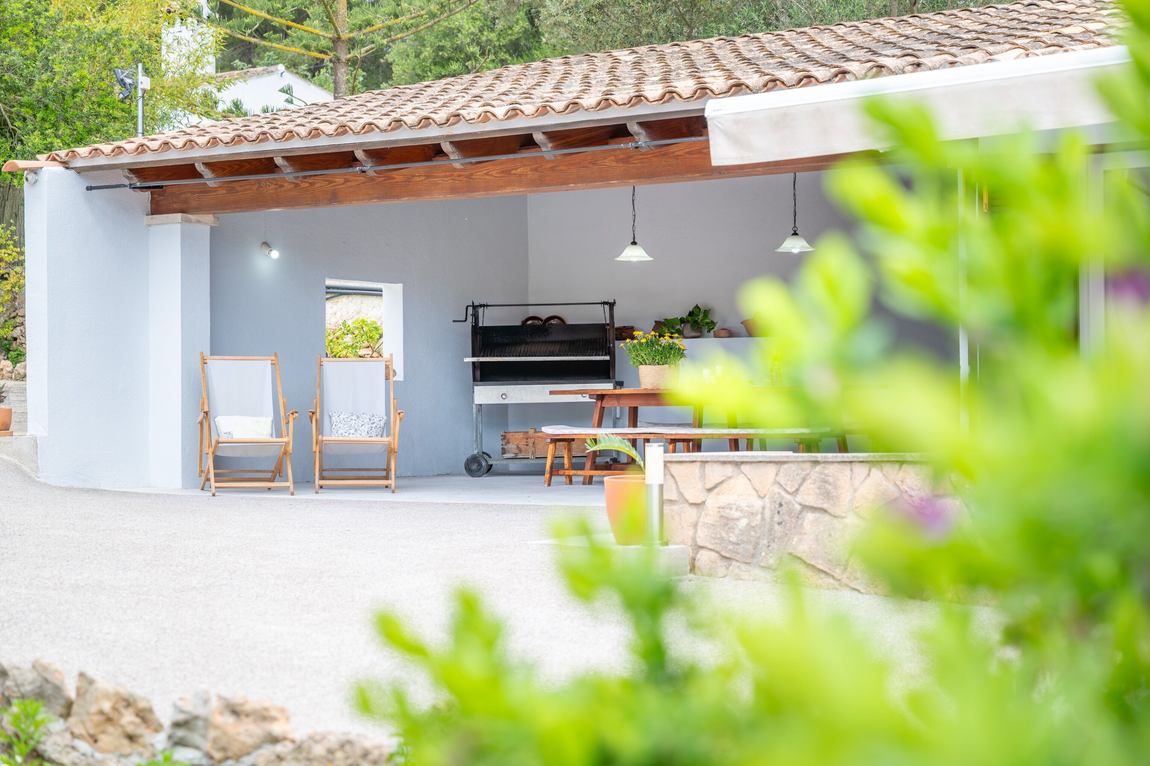 A patio area with a grill, seating, and potted plants.