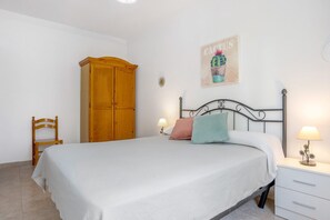 A bedroom with a bed, wooden wardrobe, bedside table, and a wall decoration.