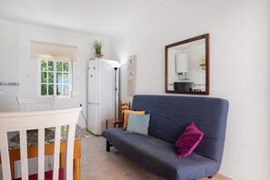 A room with a sofa, a dining table, and a refrigerator.