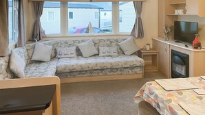 A cozy room with a sofa, a TV, and a table with a patterned tablecloth. - 3 bedroom accommodation in Heysham, near Lancaster (Heysham, near Lancaster)