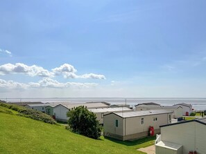 A row of mobile homes with a grassy hill and a clear sky. - 3 bedroom accommodation in Heysham, near Lancaster (Heysham, near Lancaster)