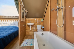 A compact room with a bed, a sink, a toilet, and a bathtub.
