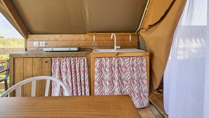 Un petit espace cuisine avec un plan de travail en bois, un évier et des rideaux à motifs.