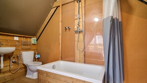 Un intérieur en bois avec une baignoire, des toilettes et un lavabo.