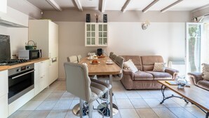 A modern kitchen with a dining area, a sofa, and a coffee table. - Country House 'Le Mas' with Shared Pool, Wi-Fi, and Air Conditioning (Graveson)