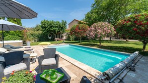 A swimming pool with surrounding patio furniture, a hammock, and lush greenery. - Country House 'Le Mas' with Shared Pool, Wi-Fi, and Air Conditioning (Graveson)