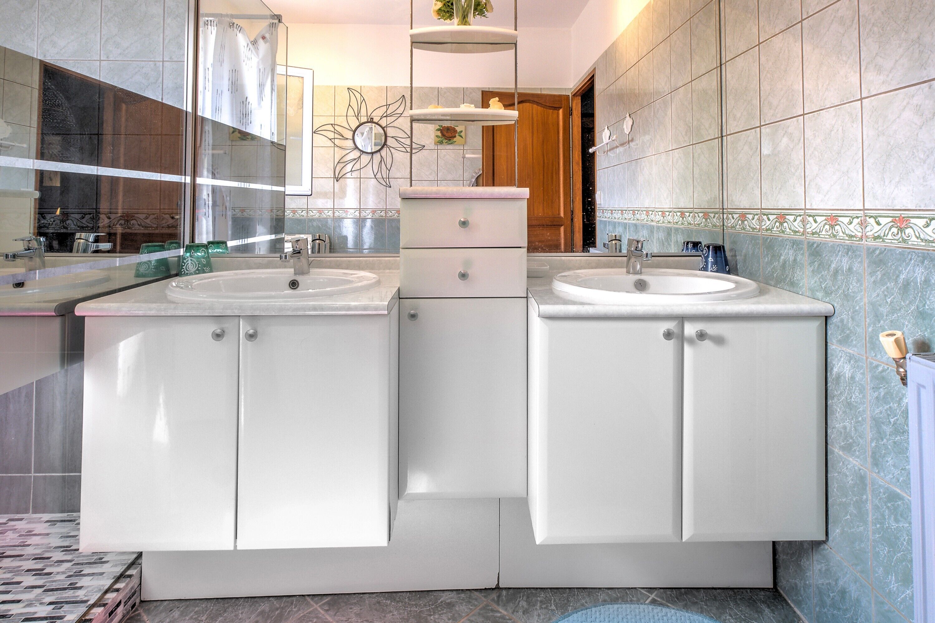 Un baño con dos lavamanos, un espejo y un adorno en la pared.