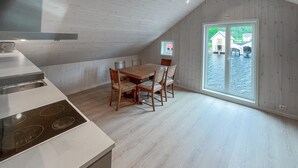 A kitchen with a dining area, wooden flooring, and a large window with a view of boats. - 2 bedroom beautiful home in Feda (Feda)