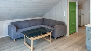 A loft-style room with a gray sectional sofa, a glass-top coffee table, and a green door. - 2 bedroom beautiful home in Feda (Feda)