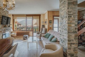 Ein Wohnzimmer mit Kamin, einer Couch, einem Couchtisch und einem an der Wand befestigten Fernseher.