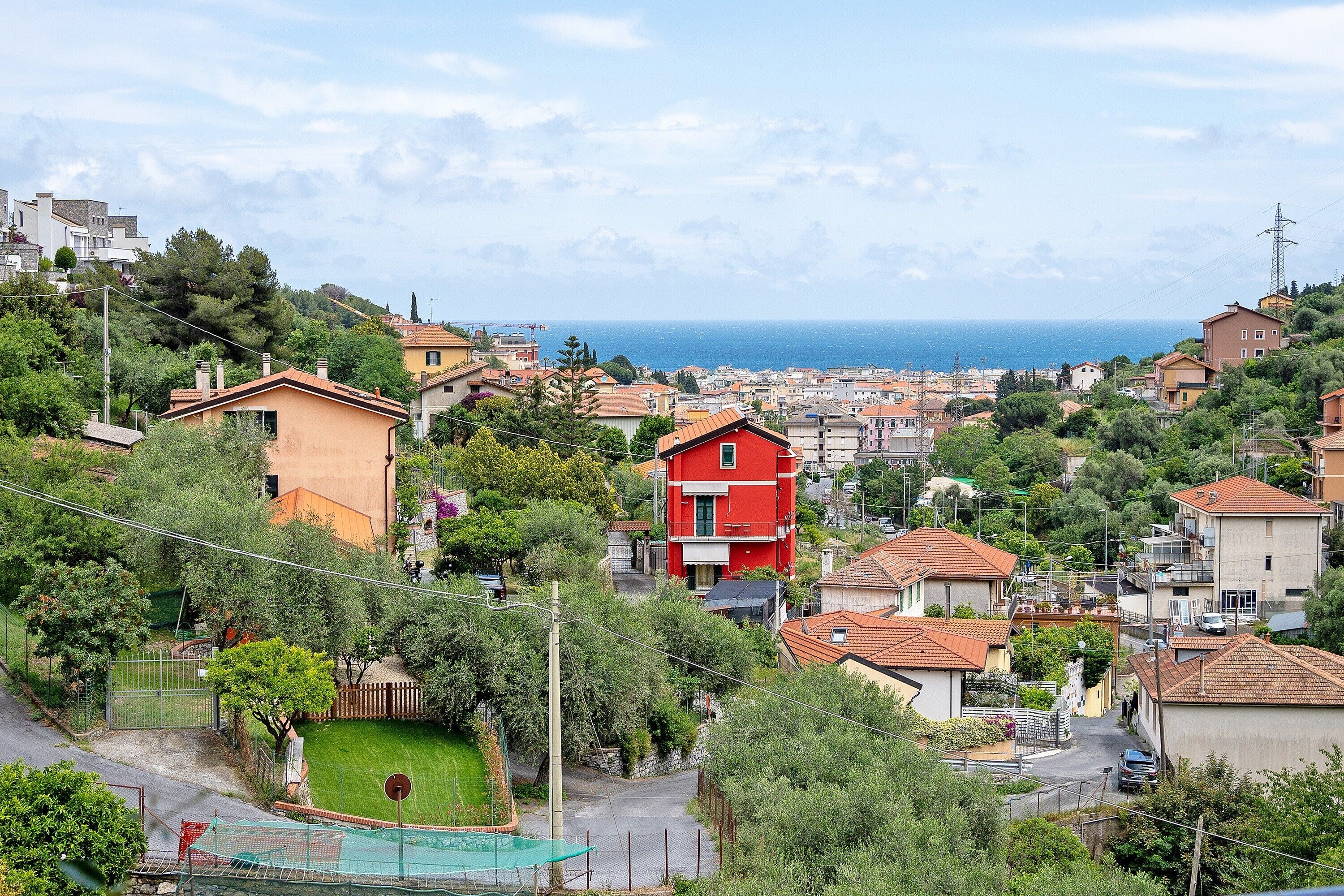 Zona residencial amb cases, un edifici vermell i vista al mar.