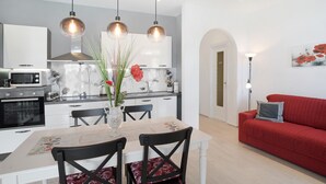 A modern kitchen with a dining area, a red sofa, and a vase with flowers.
