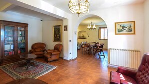 Un salon spacieux avec une cheminée, des fauteuils en cuir, un coin repas et une bibliothèque.
