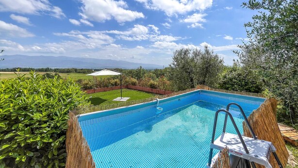 Une piscine rectangulaire à l’eau d ’un bleu limpide, entourée d’une végétation luxuriante et d’une clôture en bois.