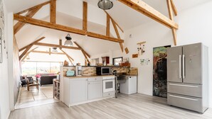 Una amplia cocina estilo loft con vigas de madera a la vista, un refrigerador grande y vista al área de estar.