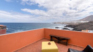 A balcony with a view of the ocean and a mountain, a wooden bench, and a small table. - Holiday Apartment 'Siempreviva' with Shared Pool and Wi-Fi (Gáldar)