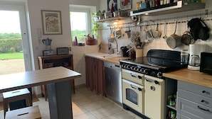 Une cuisine avec une table en bois, un poêle et divers ustensiles de cuisine accrochés au mur.