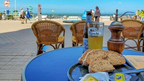 A table with a bottle of Blanche de Naumer, slices of bread, and butter on a beachside setting. - Nice apartment in Oostende with WiFi (Oostende)