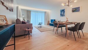 A modern living room with a sofa, dining table, and chairs, a TV, and artwork on the walls. - Nice apartment in Oostende with WiFi (Oostende)