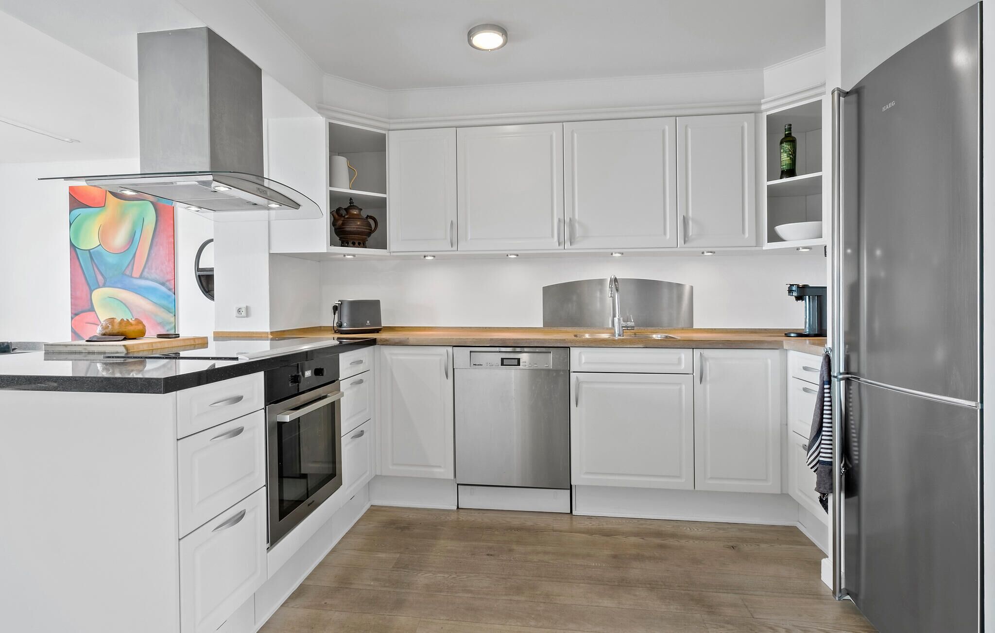 Una cocina moderna con armarios blancos, electrodomésticos de acero inoxidable y una encimera de madera.