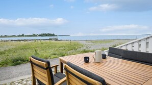A wooden table and chairs with a view of the sea and a distant island.