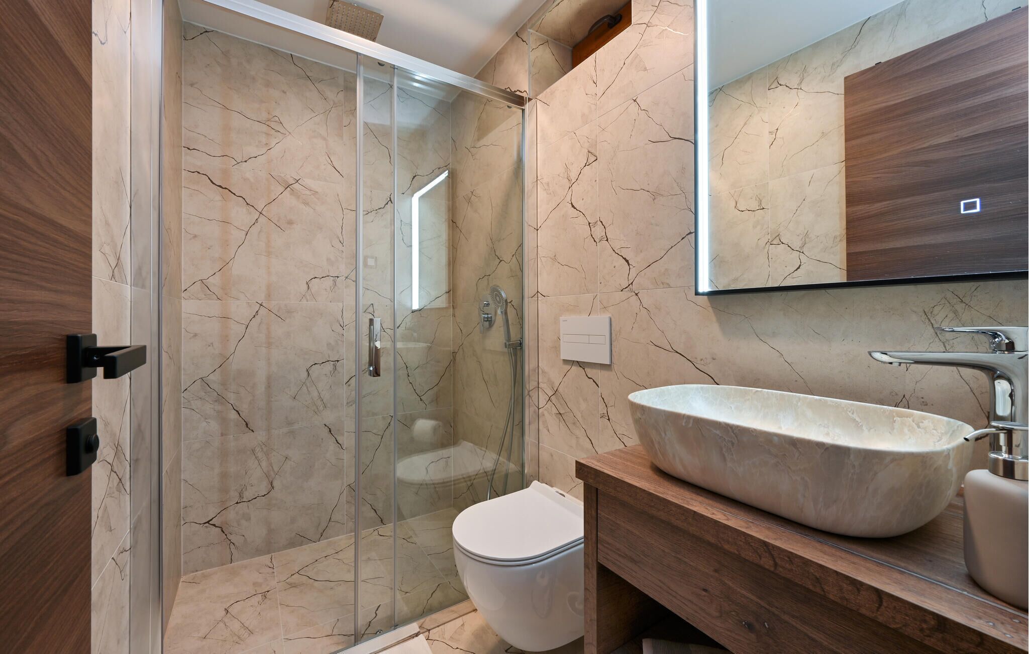 Une salle de bain moderne avec une douche à parois de verre, un meuble-lavabo en bois et un grand lavabo sur pied.