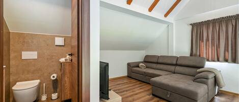 Ein modernes Wohnzimmer mit einem Ecksofa, einem Flachbildfernseher und einer Holzzieldecke.