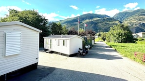 Ein Caravanpark mit Mobilheimen, einem Kiesweg und Bergen im Hintergrund.