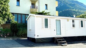 Ein Hotelgebäude mit Balkon und ein Mobilheim davor.
