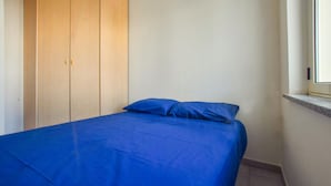 Une chambre à coucher avec un lit, une armoire en bois et une fenêtre.