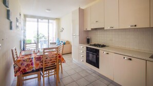 Une cuisine comprenant un coin repas, avec une table et des chaises, une cuisinière et des placards.