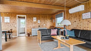A cozy wooden interior with a sofa, a dining table, and a kitchen area.