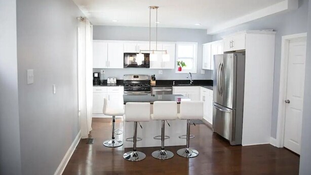 A modern kitchen with white cabinets, stainless steel appliances, and a central island with bar stools.