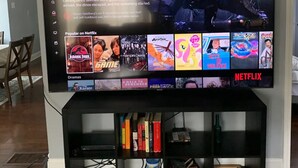 A flat-screen TV mounted on a wall displaying the Netflix interface with various show thumbnails.