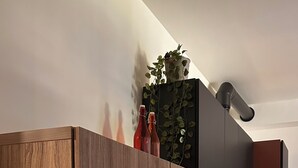 A modern kitchen with wooden cabinets, a built-in oven, and a coffee machine.